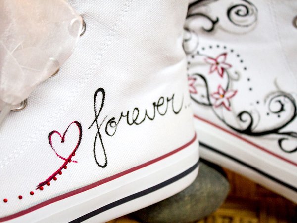 Großaufnahme von Hochzeitssneakern mit Blumen und Rankenmuster und dem Schriftzug "love" " forever"